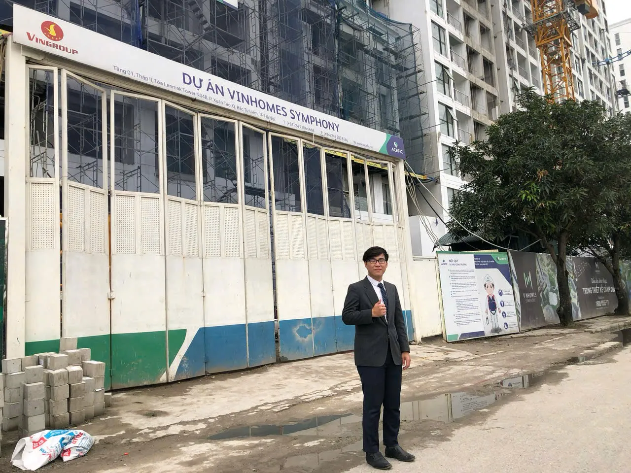 團隊人員站在河內施工中建案工地圍籬前